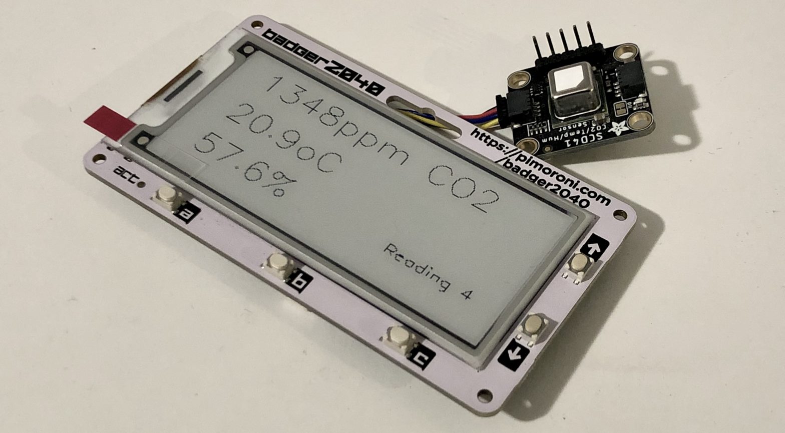 A photograph of the Badger2040 e-ink display connected via a Qwiic cable to an SCD-41 Carbon Dioxide sensor